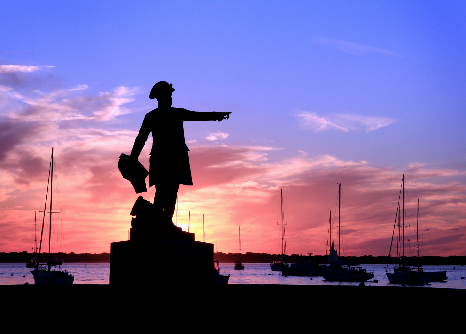 Sunset view of Newport harbor with silhouette of statue