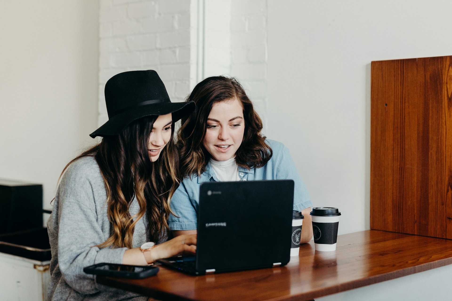 Two women planning a trip using AI on a laptop