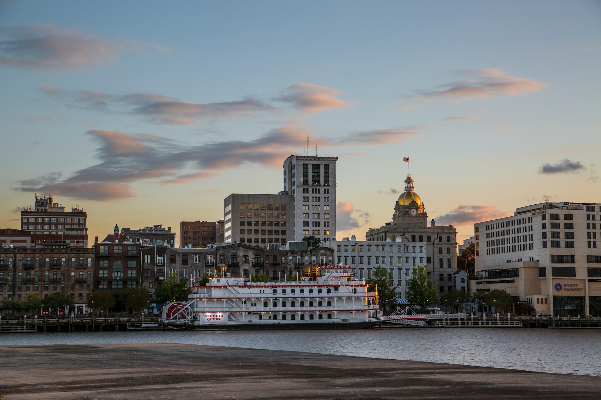 Sunset view of Savannah's riverfront with the Georgia Queen riverboat and historic buildings