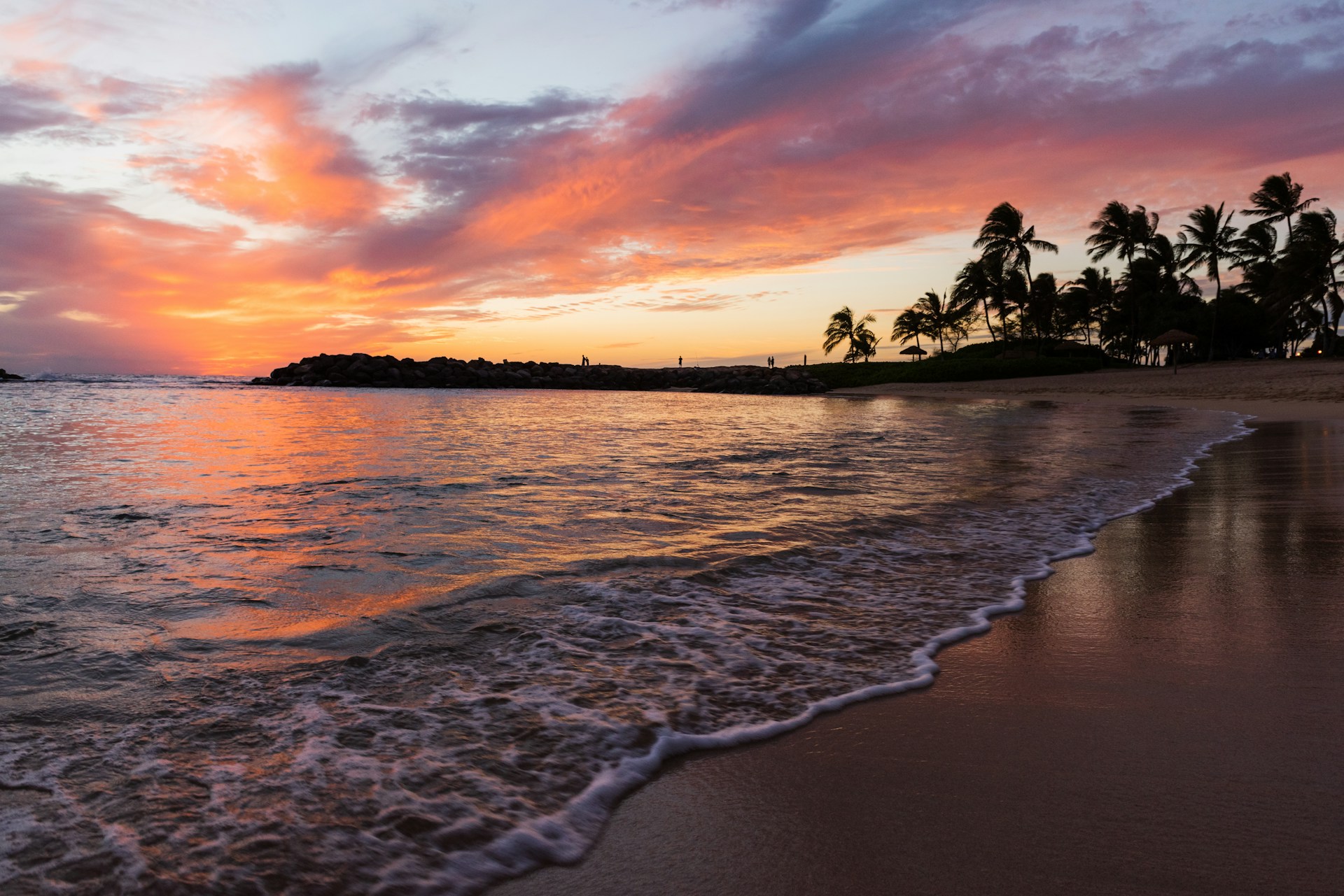 Beautiful Hawaiian beach at sunset with palm trees and vibrant orange sky