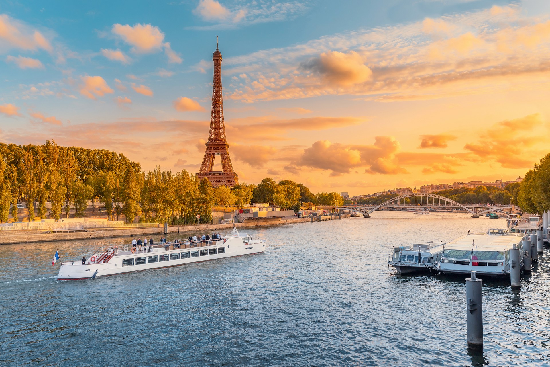 Sunset view of Paris with the Eiffel Tower and boats on the Seine River