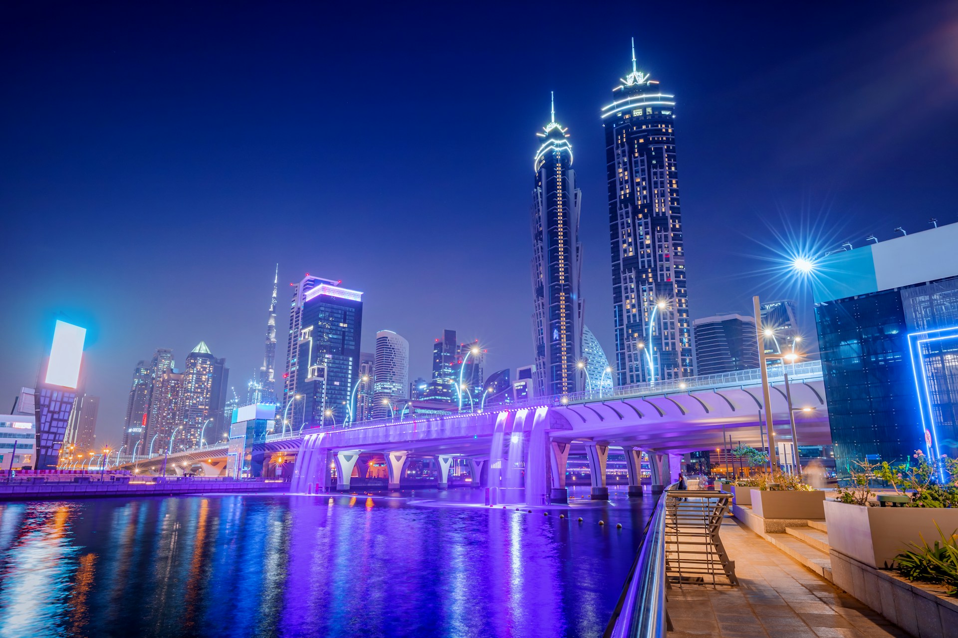 Dubai skyline at night with illuminated skyscrapers and a purple-lit bridge